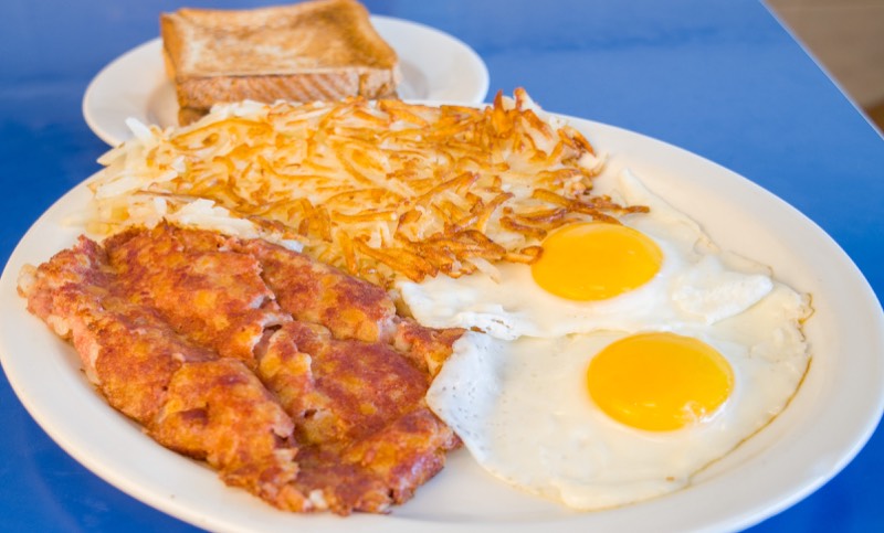 Corned beef hash with two sunny-side-up eggs, hash browns, and toast.