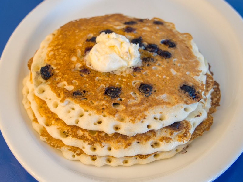 Tall stack of blueberry pancakes with a melting pat of butter.