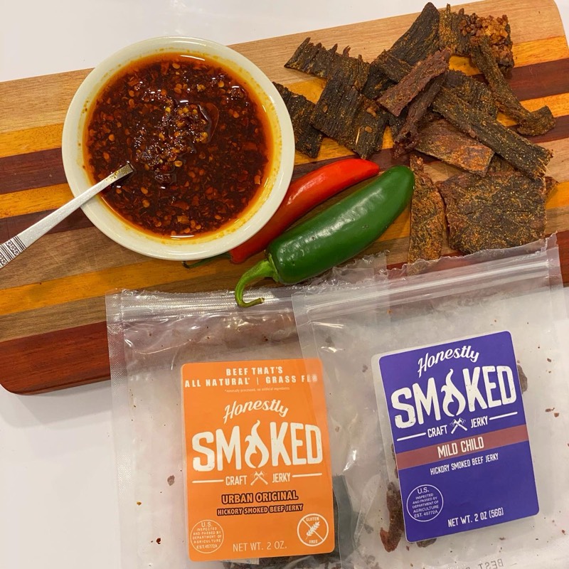 Overhead flat-lay of Honestly Smoked jerky strips with chili oil and fresh chiles.